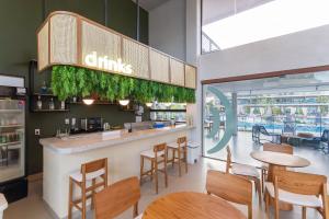 ein Restaurant mit einer Bar mit Holztischen und -stühlen in der Unterkunft Malia Beach #D105 - Muro Alto por Carpediem in Ipojuca