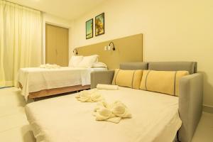 ein Hotelzimmer mit zwei Betten und Handtüchern auf einer Couch in der Unterkunft Malia Beach #D105 - Muro Alto por Carpediem in Ipojuca + 33 Fotos