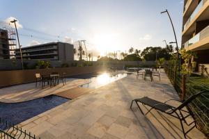 eine Terrasse mit Tischen und Stühlen an einem Gebäude in der Unterkunft Malia Beach #D105 - Muro Alto por Carpediem in Ipojuca