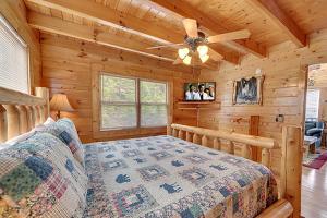 Un dormitorio tipo cabaña de madera con una cama y un ventilador de techo. en Eagles Nest by Venture Smoky Mountains, en Sevierville