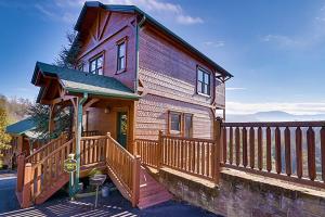 a wooden cabin with a porch and a fence at Elizabeths View II by Venture Smoky Mountains in Gatlinburg