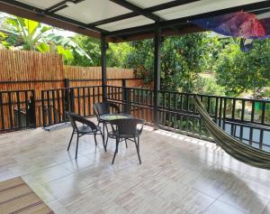 a patio with a hammock and a table and chairs at Serenity House with Large terrace in Ban Nok