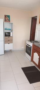 a kitchen with a stove and a white tile floor at Appart Vue Mer in Îlet à Christophe