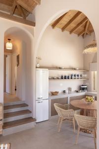 a kitchen with a table and a white refrigerator at Villa Nanoula & Villa Stella Twin Villas Retreat in Skopelos Town