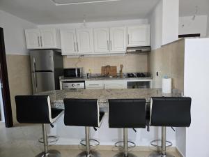 a kitchen with white cabinets and black bar stools at Atlantique Assilah Vue Mer, Piscines, Clim & Wi-Fi in Asilah
