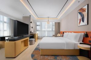 a bedroom with a bed and a flat screen tv at Hilton Garden Inn Huai'An Huaiyin in Huai'an