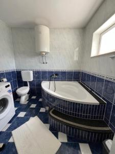 a blue tiled bathroom with a tub and a toilet at Apartman Jugo in Kaštela