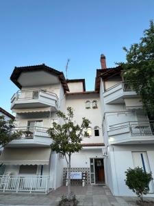 a white building with a tree in front of it at Levanta apartment in Asprovalta