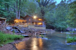 a log cabin with lights on a river at Waterfalls Edge by Venture Smoky Mountains in Pigeon Forge
