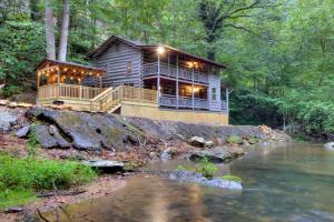 a wooden house with lights on the side of a river at Waterfalls Edge by Venture Smoky Mountains in Pigeon Forge