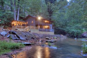 a log cabin in the woods next to a river at Waterfalls Edge by Venture Smoky Mountains in Pigeon Forge