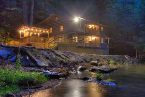 a large house with lights on the side of a river at Waterfalls Edge by Venture Smoky Mountains in Pigeon Forge +43 photos