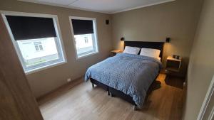 a bedroom with a bed with two pillows and two windows at Comfortable and Renovated Apartment - Sunny balcony, Central, Free parking in Haugesund