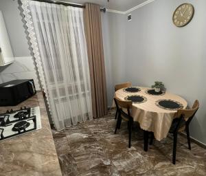 a dining room table with chairs and a clock on the wall at Однокімнатна квартира in Chernivtsi +6 photos