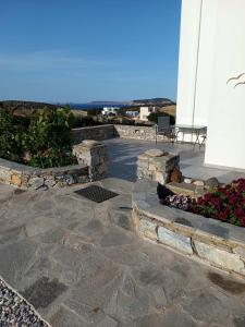 a stone patio with flowers and a building at Amalthea Schinousa in Schinoussa