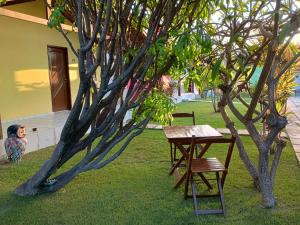 a table and two chairs next to a tree at Chalés do Otto e Karine in Canoa Quebrada