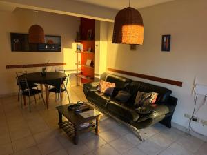a living room with a black leather couch and a table at Departamento con Balcón y Asador in Río Cuarto