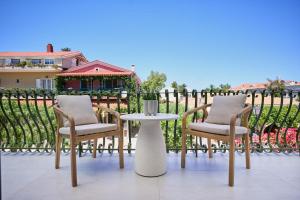 two chairs and a table on a patio with a fence at Bougainvillea Bliss in Skala Kefalonias