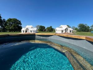 a pool of water with two tents in the background at GreenFeilds Glamping Stargazing Yurts and Outdoor Spa in Milwich