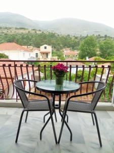 a table and chairs on a balcony with a vase of flowers at Stamoulis Apartments in Agia Effimia