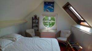 1 Schlafzimmer mit einem Bett, 2 Stühlen und einem Fenster in der Unterkunft B&B Dreamcottage in Knokke-Heist
