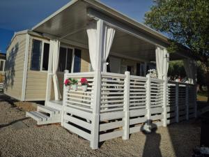 a tiny house with a white fence and flowers at Mobile home San Antonio in Sveti Filip i Jakov
