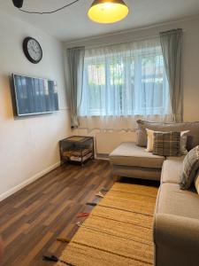 a living room with a couch and a clock on the wall at Grundy House in Uxbridge