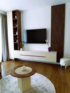 Una sala de estar con un televisor y una mesa. en LanDan Planet - free parking, en Niš