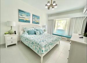 a white bedroom with a bed with blue pillows at Beautiful Two bedrooms apartment in Punta Cana