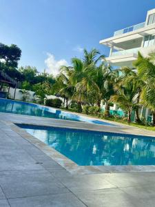 a swimming pool with palm trees in front of a building at Beautiful Two bedrooms apartment in Punta Cana
