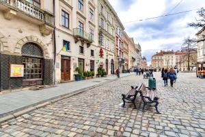 Una calle adoquinada con dos bancos y edificios. en Duplex on Main Square, en Leópolis