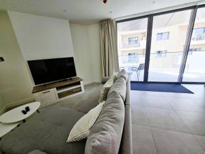 a living room with a couch and a flat screen tv at Brand New 1BR Pool & Jacuzzi On Site Parking Suite One in Gibraltar