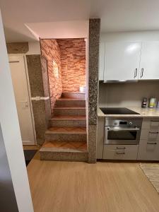 a kitchen with a staircase with a brick wall at Chalé da Fonte - T2 in Geres