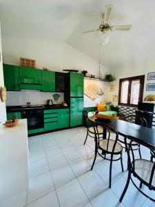 a kitchen with green cabinets and a table and chairs at Sea&Sage 4 Spiagge Raggiungibili a piedi, Per famiglie con tutti i servizi in Porto San Paolo