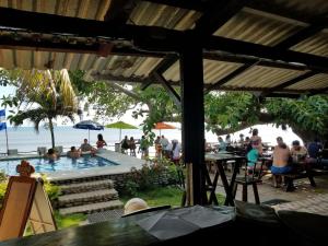 a group of people sitting around a swimming pool at Hotel Casa Miramar in Tamanique