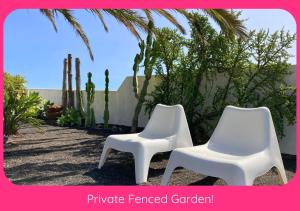 two white chairs sitting next to a wall with cactus at Full Relaxation - Private Villa - Sea View - Stunning Garden - 2 Terraces - 2 Bedrooms - Wifi - Parking - Washing Machine in Güime