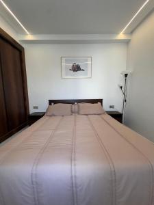 Bel appartement face là mer في القنيطرة: سرير كبير في غرفة بيضاء مع اعتراف +32 صورة