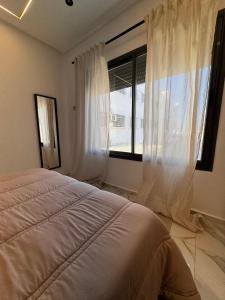 Bel appartement face là mer في القنيطرة: غرفة نوم بها سرير ونافذة كبيرة