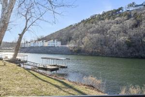 a river with a dock and a building on a hill at Foggy River Retreat - For 16 in Hollister