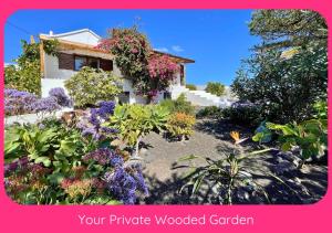 a garden with flowers in front of a house at Full Relaxation - Private Villa - Sea View - Stunning Garden - 2 Terraces - 2 Bedrooms - Wifi - Parking - Washing Machine in Güime