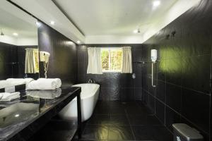 un bagno nero con vasca e lavandino di El Faro Containers Beach Hotel a Manuel Antonio