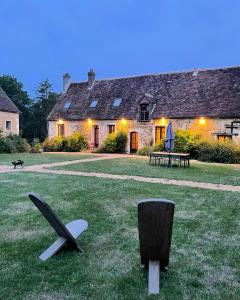 a house with two chairs in the grass in front of it at Authentique maison de famille in Val-au-Perche