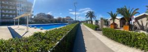 a sidewalk next to a swimming pool with trees and buildings at Adriatico 98 in Fano
