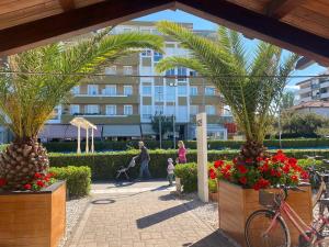 a family walking through a garden with palm trees and a building at Adriatico 98 in Fano
