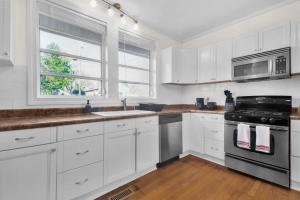 a kitchen with white cabinets and a stove top oven at Ping-Pong & Huge Yard Central- Fayetteville Pearl in Fayetteville +25 photos