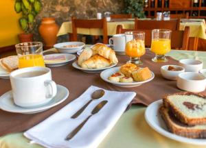 a table topped with plates of food and cups of coffee at Hotel Los Sauces in Cafayate