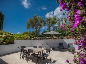 un patio con tavolo, sedie e ombrellone di Villa les Oiseaux a La Garonnette-Plage