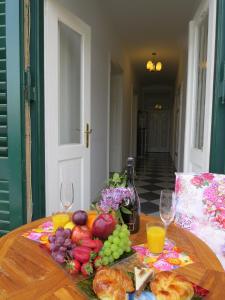 un tavolo con un mucchio di frutta e bicchieri da vino di Apartment Kamelija a Opatija