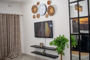 a living room with a tv and clocks on the wall at Kanana Villas - Maun Luxury One Bedroom Apartment in Maun