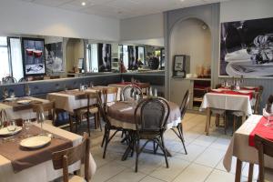 a dining room with tables and chairs in a restaurant at Hôtel de la Grotte in Aix-les-Bains